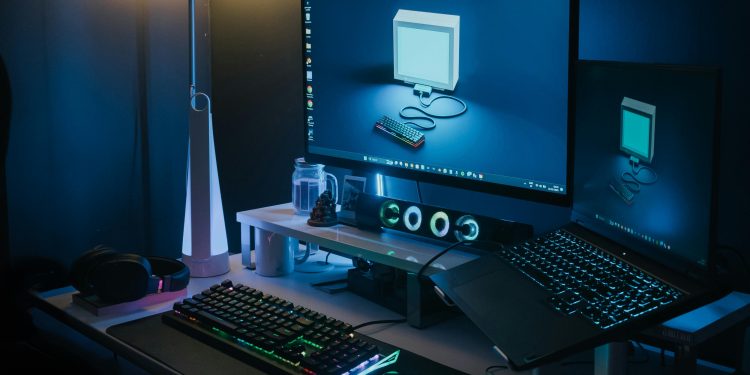 A stylish home office featuring a desktop, laptop, and ambient lighting. Ideal for tech professionals.